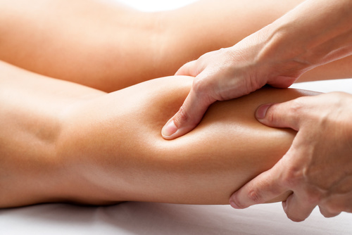 Therapist applying pressure with thumb on female calf muscle.